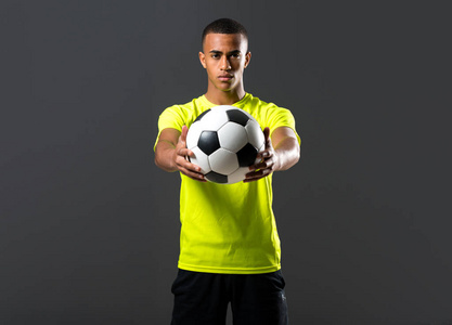 足球运动员与深色皮肤玩抓住一个球, 他的手在黑暗的背景
