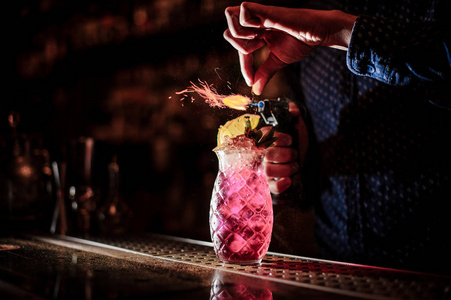 酒保手做一个甜美新鲜的草莓莫吉托夏季鸡尾酒与烟雾注在酒吧的黑暗背景