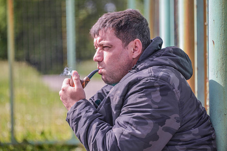 那个男人正在抽烟斗, 特写, 在凉爽的刮风的天气里, 烟雾在空中飞翔.