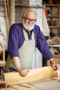 戴眼镜和便装的老人喜欢用木头干活。