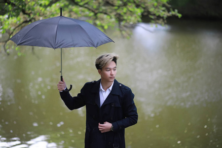 春天下雨的天气和一个年轻的人用雨伞