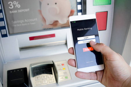 无需使用信用卡就能从 Atm 取款机取款。手持手机和手机银行登录屏幕的人