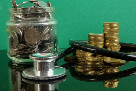 医疗费用概念用听诊器和硬币. 在绿色背景下