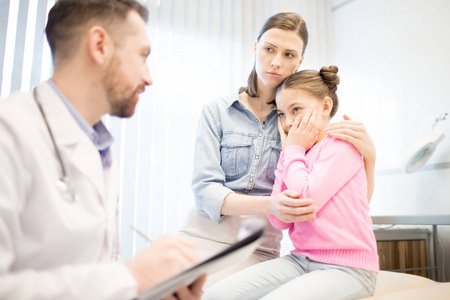焦急的妇女和她的女儿听医生的意见在任命期间诊断