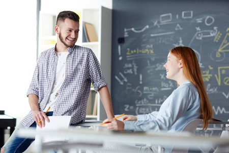 快乐的男孩和女孩在休息前聊天在他们的大学课堂上上课照片