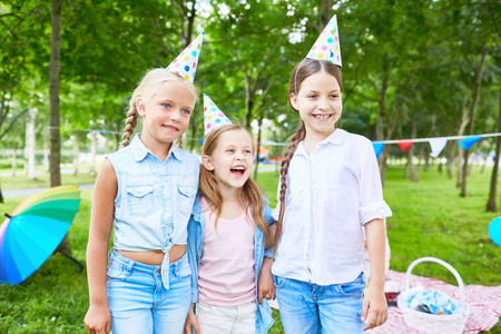 三小女孩在生日帽有乐趣和享受党在公园在夏季周末