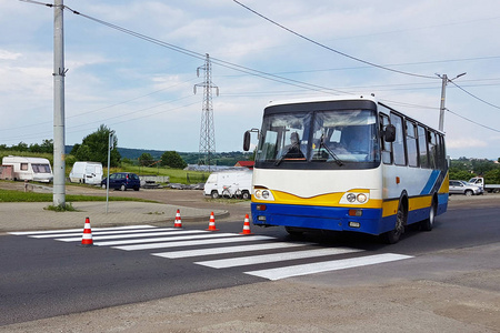 客车乘坐的新装修行人过路处仍未干红。道路标志对交通的限制。更新道路行人标志。灰色沥青上的发光涂料