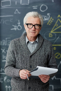 自信的灰色头发的老师在眼镜和聪明的 casualwear 看照相机由黑板