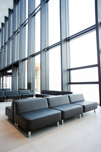 现代机场候诊区大窗户上的黑色真皮座椅或沙发排