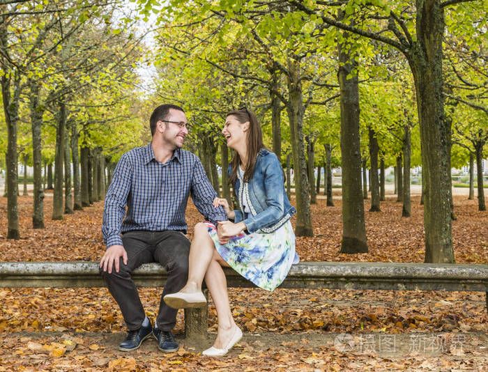 可爱的情侣在公园的一块石头长凳上玩得很开心秋天