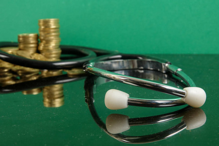医疗费用概念用听诊器和硬币. 在绿色背景下