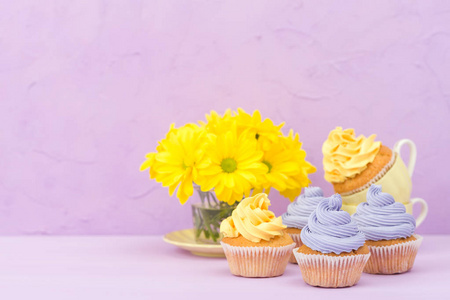 用甜黄色和紫罗兰色奶油和菊花在紫罗兰色的背景上装饰的蛋糕。Copyspace 地区。可用于问候母亲日和情人节贺卡。简约理念