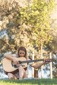 hermosa mujer tocando la guitarra en el parque美丽的女人，在公园里的吉他