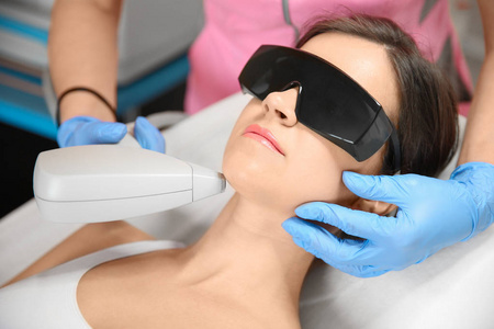 青年女子在美容院接受激光脱毛程序照片