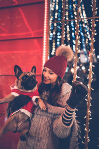 在圣诞节前夕与法国斗牛犬的年轻妇女在街道上