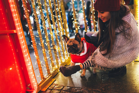 在圣诞节前夕与法国斗牛犬的年轻妇女在街道上