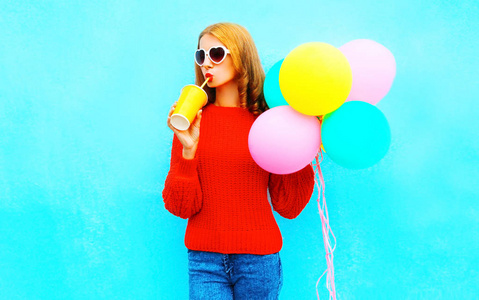凉爽的快乐时尚的女孩与空气气球饮料果汁在蓝色背景