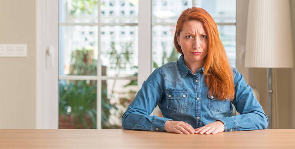 红发的女人在家里怀疑和紧张, 皱着眉头心烦因为问题。消极的人