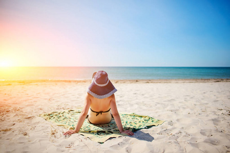 在热带海滩放松的蓝色帽子的年轻妇女