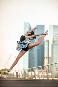 美丽的年轻女孩在城市跳舞, 与摩天大楼的背景