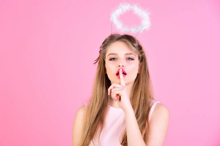 女孩天使在她的头上的光环在粉红色的背景礼服照片