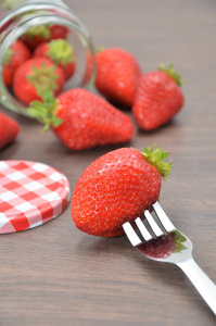 木桌上有叉子和果酱瓶的草莓