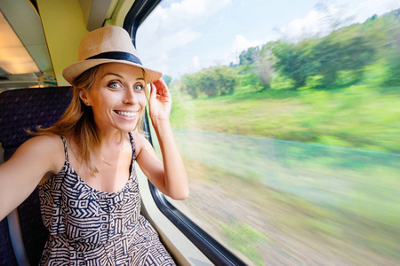 年轻漂亮的女人坐在靠近窗户的火车上乘坐自拍