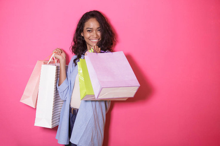 亚洲妇女的幸福肖像带购物袋粉红色背景