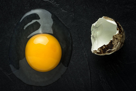 原始的残破的蛋黄在黑暗的石头背景。新鲜有机食品