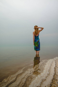 尼斯妇女站立在死海的水在乔丹和雾在周围