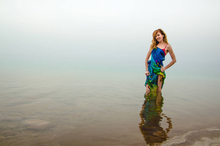 尼斯妇女站立在死海的水在乔丹和雾在周围
