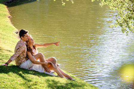 爱的夫妇坐在一起在草附近湖