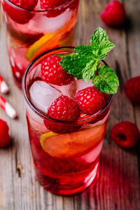 树莓莫吉托柠檬汁与石灰和新鲜薄荷在玻璃上的木质背景。夏日清爽鸡尾酒