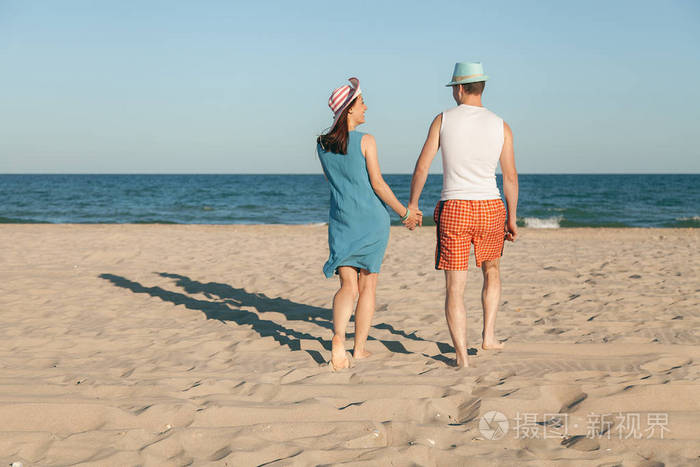 一对相爱的情侣赤脚漫步在沙滩上的沙滩上