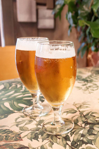 在酒吧里桌上的玻璃杯里放点泡沫的啤酒。充分玻璃和模糊的酒吧背景