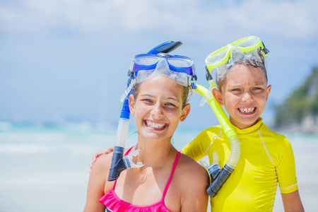 在炎热的夏日假期里, 在沙滩上玩潜水面具的兄弟姐妹肖像