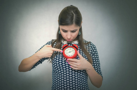 睡过头的女人手里拿着一个红色的闹钟。上班或上学迟到。睡 过头。后向概念