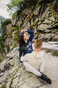 年轻夫妇坐在岩石边缘的挪威峡湾