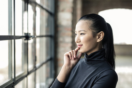 美丽的亚洲妇女看着窗外积极在工业内饰