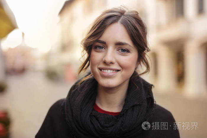 年轻美丽的女人与一个 foulard 微笑积极在街上的城市