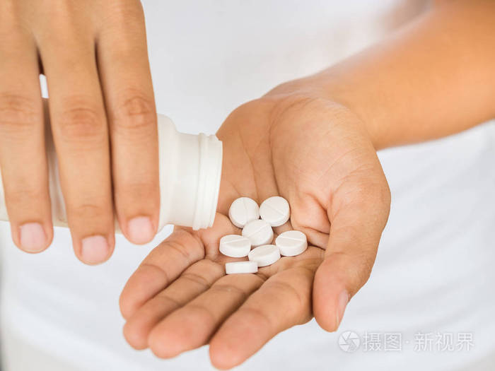 年轻女子向她的手里倒出药,胶囊或药丸.医疗保健理念