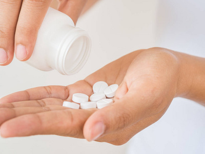 年轻女子向她的手里倒出药,胶囊或药丸.医疗保健理念照片