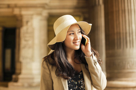 美丽的亚洲妇女在帽子上谈论智能手机