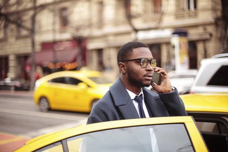 黑人商人坐出租车, 在城市的智能手机交谈