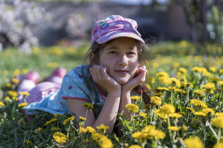小女孩躺在草地上花。户外。微笑的女孩躺在田野上与蒲公英