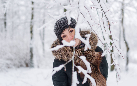 冬天在寒冷的天气在户外的年轻女子的肖像。雪下穿暖衣服的女性