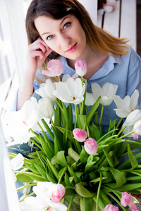 一张年轻女子的照片坐在一束花的窗户上