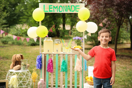 小男孩在柠檬水站在公园里