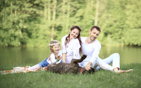 幸福的家庭带宠物狗在阳光明媚的夏日野餐。孕甾