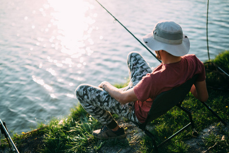 年轻人在池塘和享受的爱好钓鱼照片